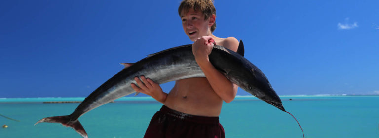 boy holding a wahoo fish he caught in Aitutaki